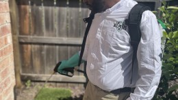 Pest control technician treating the exterior of the house for ants, spiders, and more
